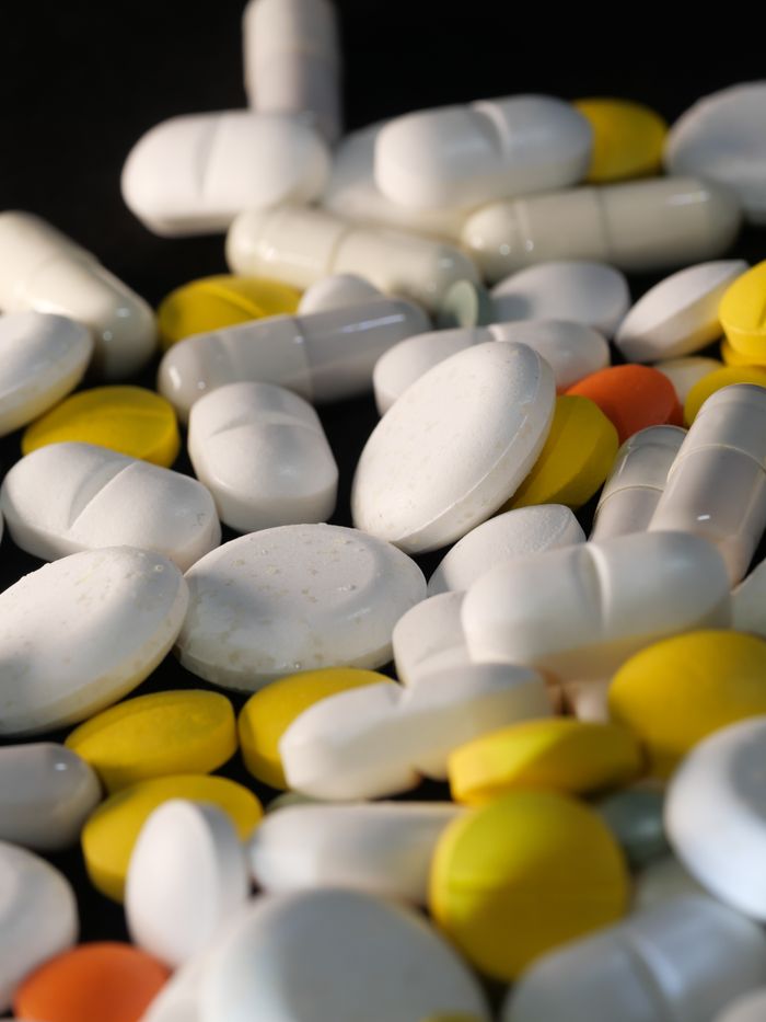 A close-up view of assorted colorful capsules and tablets on a dark background.