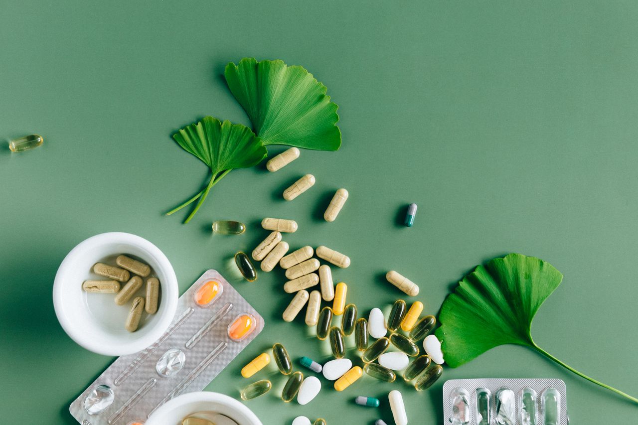 services-04 Flat lay of varied supplements and medicines with ginkgo leaves on green surface, showcasing a natural remedy concept.